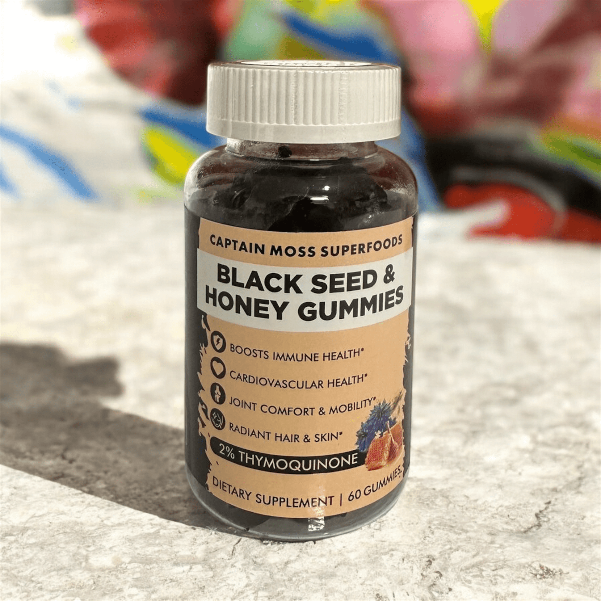 Premium Black Seed & Honey Gummies bottle on a colorful background, promoting immune and cardiovascular health, 60 gummies.